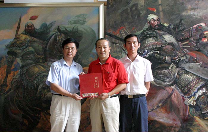 7 在北京王可伟画室，文化学者朱正明（左)向王可伟先生（中)赠送《世界关帝文化》专著，右为青年画家刘立波.JPG