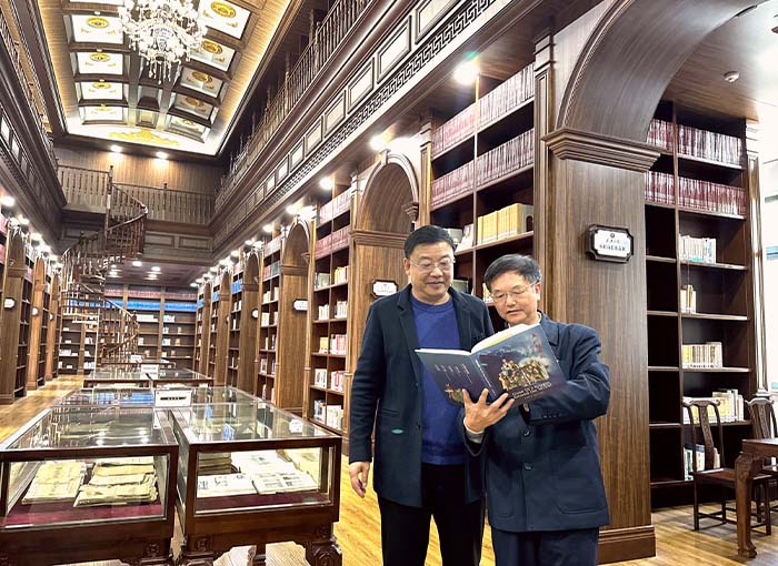 2、2023年12月5日，在武汉大学图书馆，朱正明（右）向图书馆馆长董有明介绍新书《五洲关帝图》.jpg